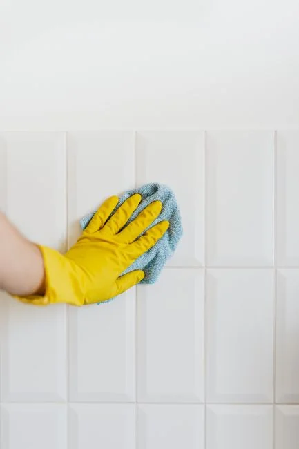 A woman in overalls cleans a wall in a stylish living room, enhancing home hygiene.